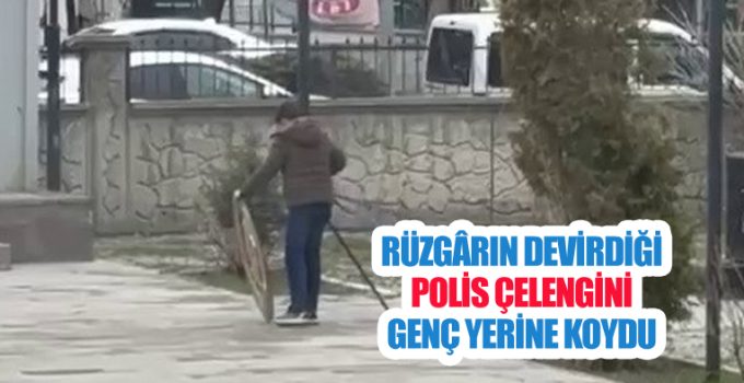 Rüzgârın devirdiği polis çelengini genç yerine koydu