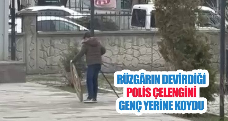 Rüzgârın devirdiği polis çelengini genç yerine koydu